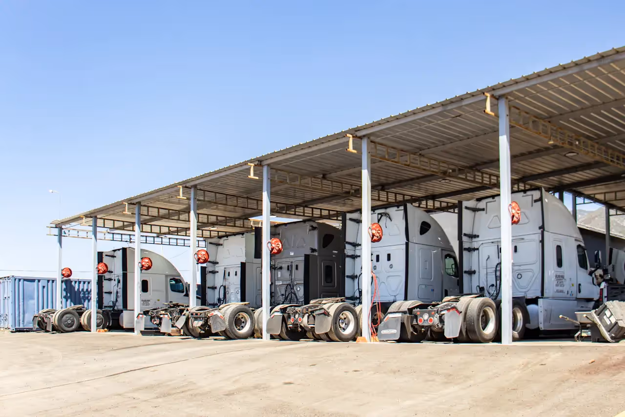 Semi-trucks parked in covered service bays for fleet maintenance at a heavy-duty repair facility.