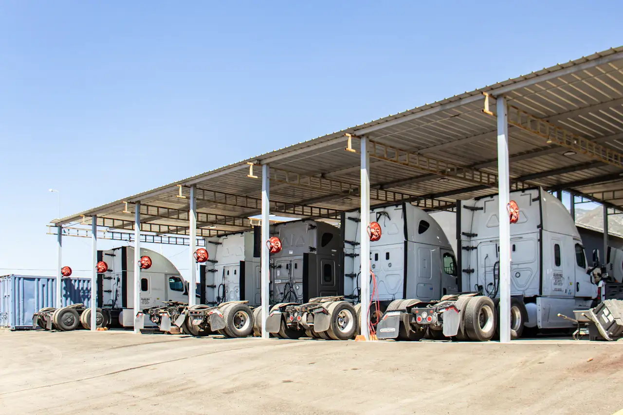 Semi-trucks parked in covered service bays for fleet maintenance at a heavy-duty repair facility.