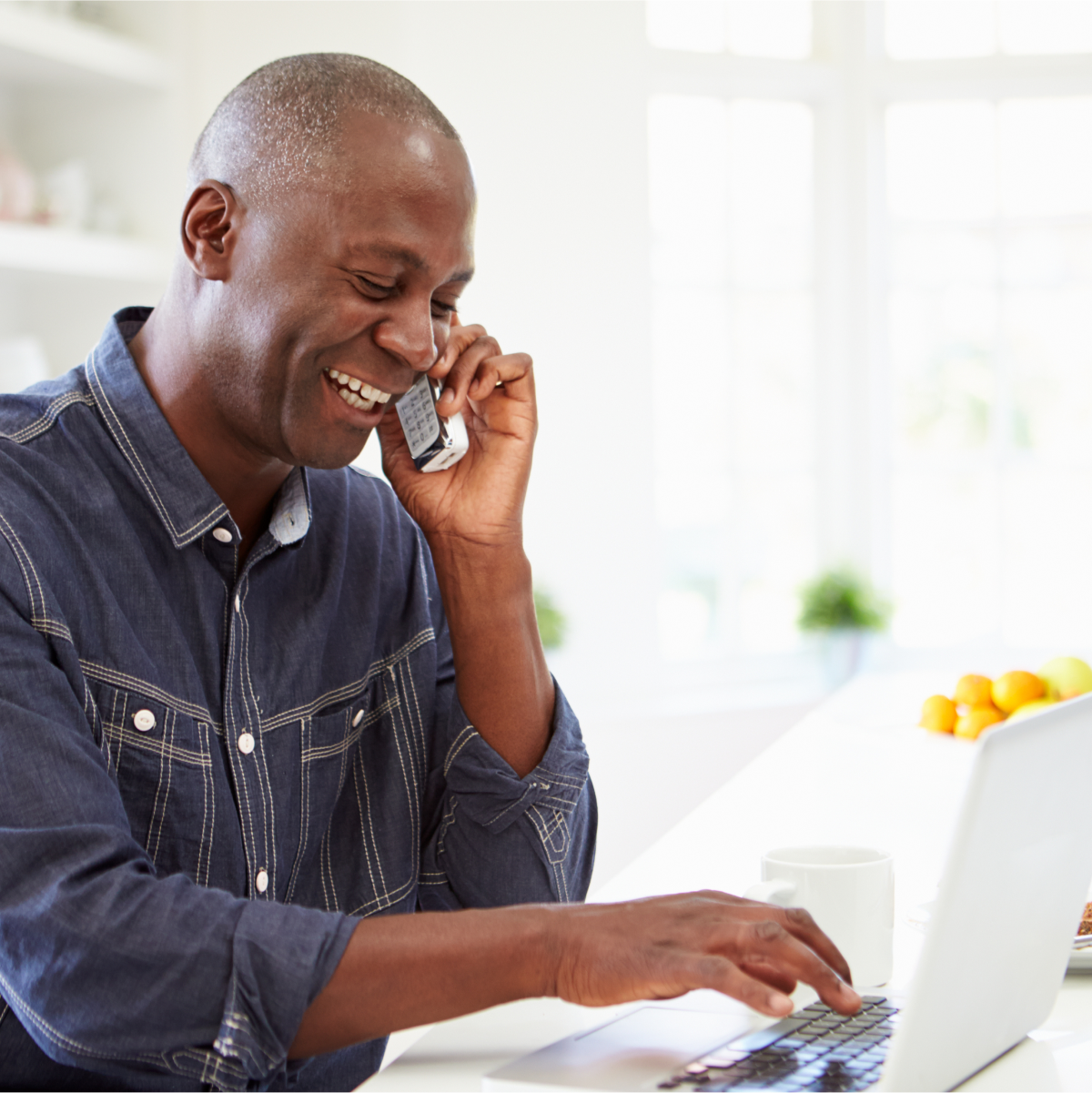 A man happy while making calls and typing on the PC.