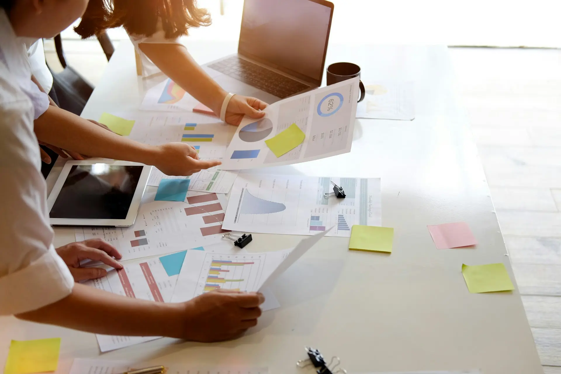 Two people from office team look at analytics graphs placed on the desk