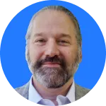 Smiling man with a beard and short hair wearing a light-colored shirt and jacket, set against a blue circular background