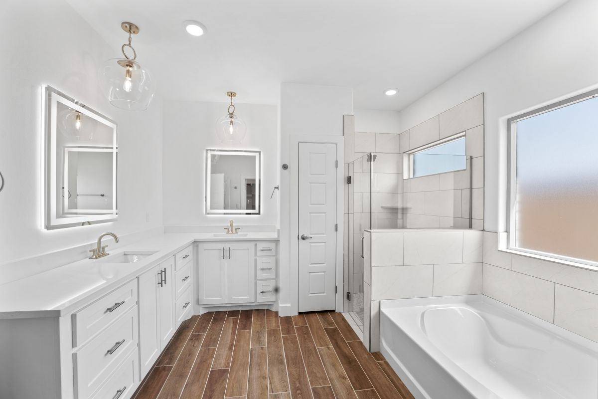 Bathroom featuring two vanities, tub and shower combo in a Purple Key Home