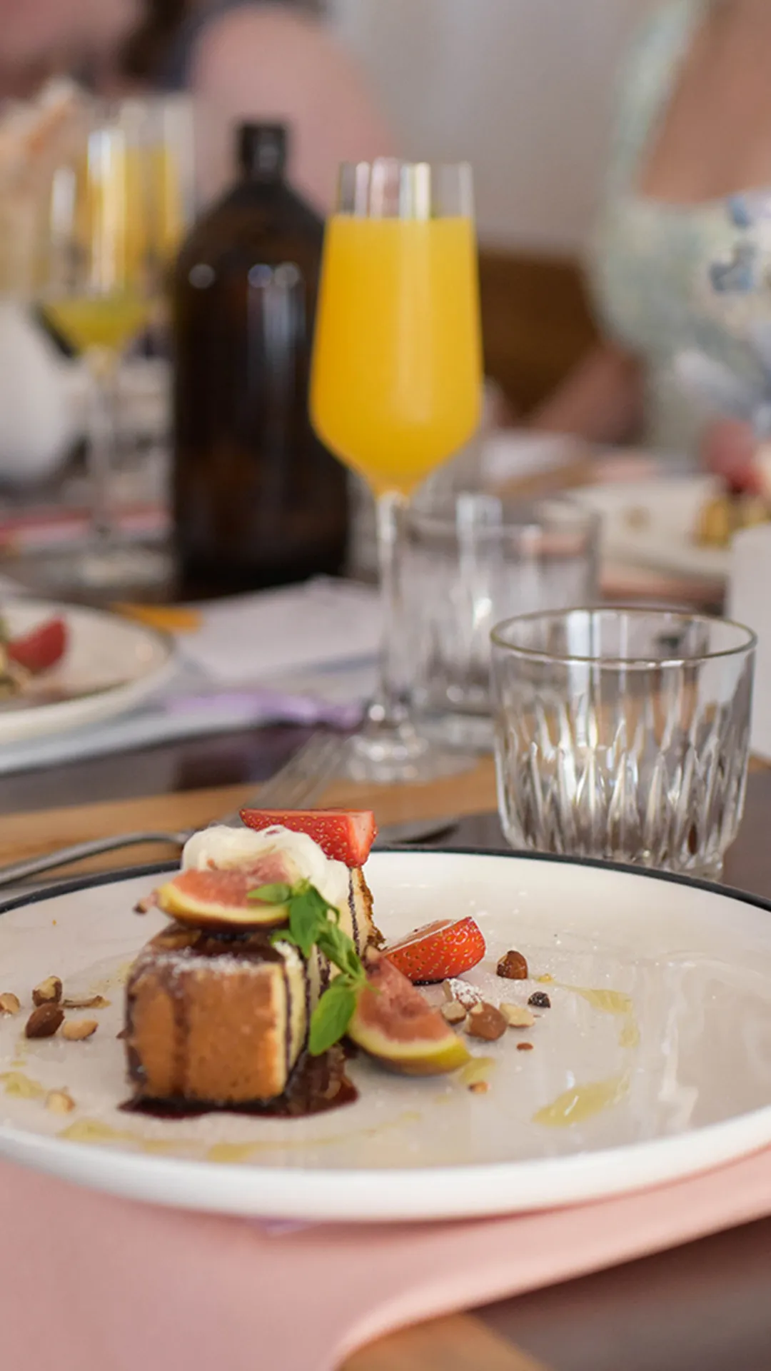 A table setting highlighting a plate with marble cake topped with strawberries, guavas and cream.