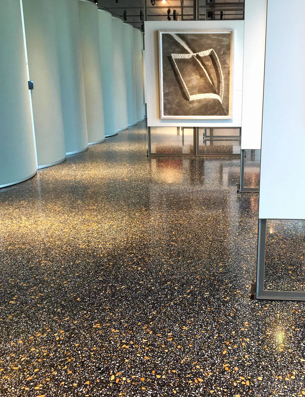 pavimento interior contínuo em terrazzo MCC aplicado em edifício de escritórios em Lisboa, com base na cor preto e agregados dourados e brancos / indoor continuous floor in MCC terrazzo system, installed in a Lisbon office building, with a dark base color and white and gold aggregates.