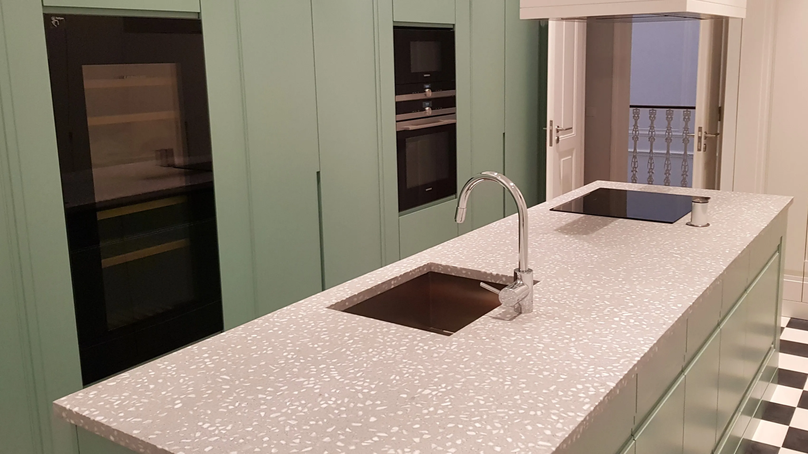 tampo para cozinha em residência privada produzida em terrazzo na cor cinzento. /  kitchen worktop for a private residence made of terrazzo in grey and white colors.
