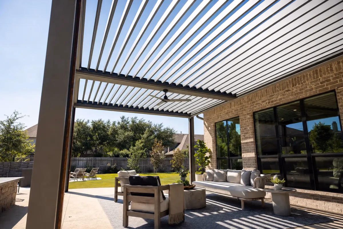 Motorized louvered pergola with open aluminum blades over a backyard patio in sunlight