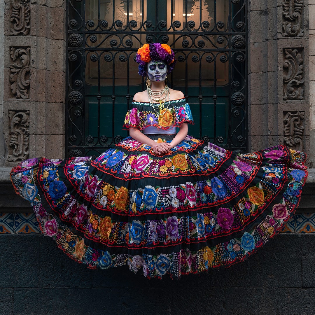 image of a mexican woman in a colorful dress with day of the dead makeup on