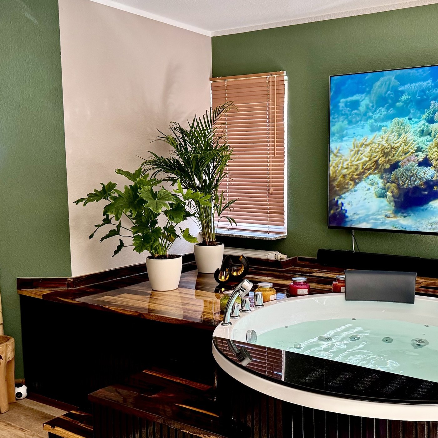 Wellness-Apartment in Mainz: Whirlpool, Sauna und großes Display in einem Raum.
