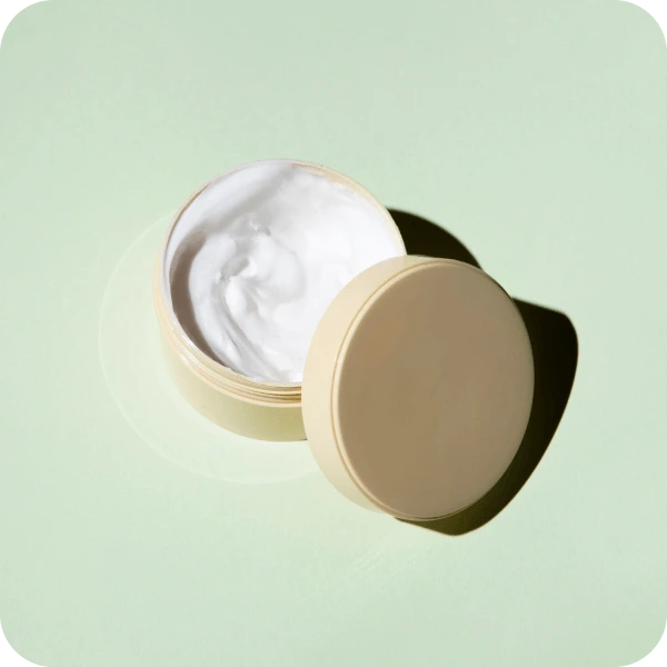 Green background with open tub of cream