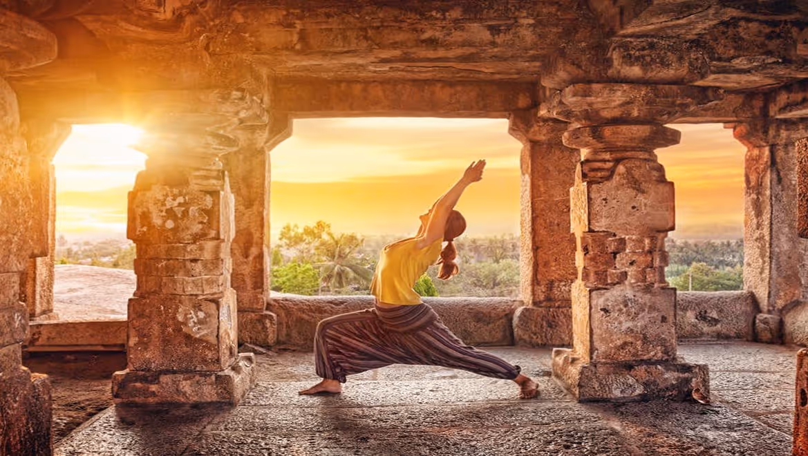 A woman doing yoga at sunset in a beautiful temple.