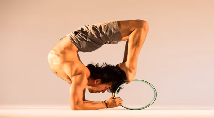 Yogi man doing yoga pose with yoga wheel