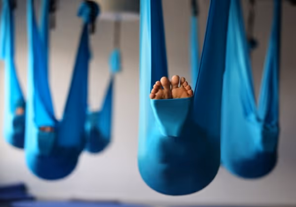 A group of yogis doing aerial yoga on a hammock