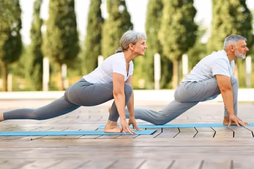 Middle-aged man and woman doing yoga to relieve sciatica pain