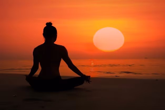 Lady Yogi in the lotus position facing the sunset