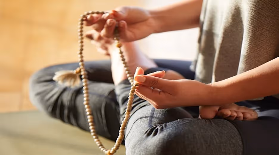 Yogi lady sitting in lotus position chanting with rosary