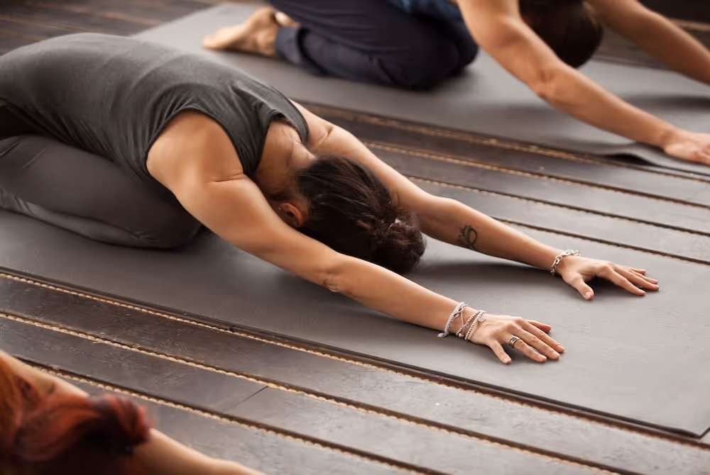 Yogi woman doing Balasana on mat in yoga class