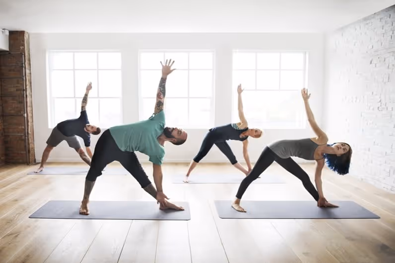 Two yogi ladies and two yogi gentlemen doing asanas on mats in yoga class