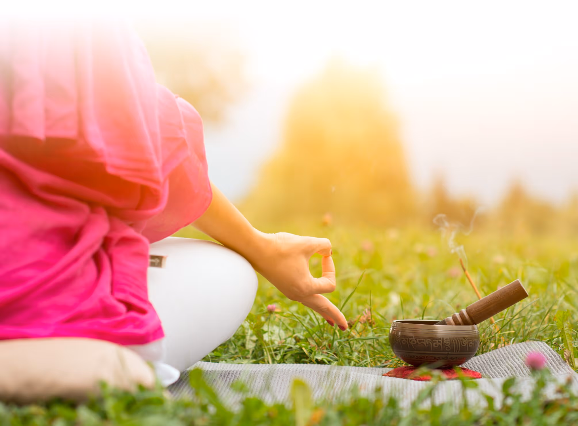 Person in lotus position meditating in nature and Tibetan bowl