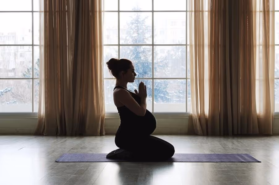 Pregnant woman on mat doing yoga and meditation