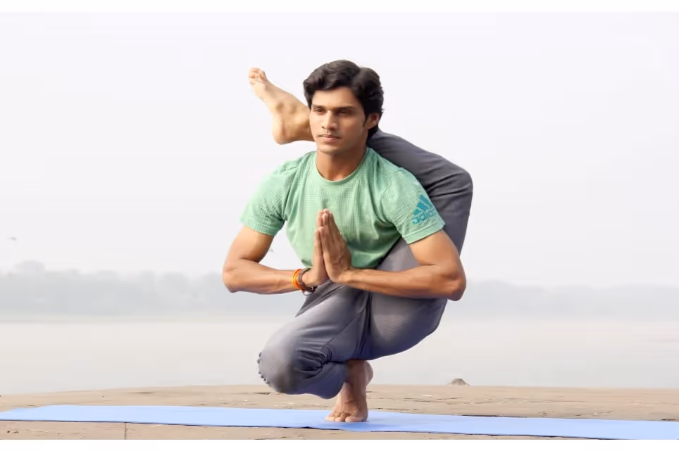 Yogi man sitting on a mat with the other leg behind his neck