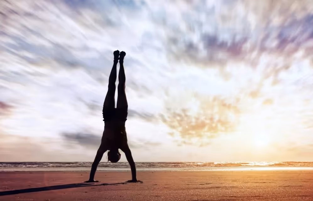 Yogi standing on his hands by the sea