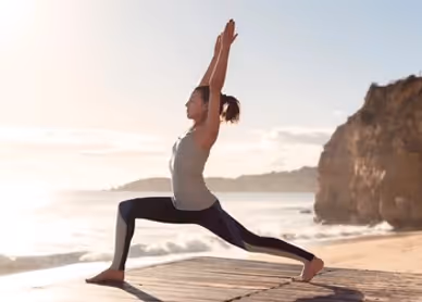 Yogi lady doing high lunge by the sea
