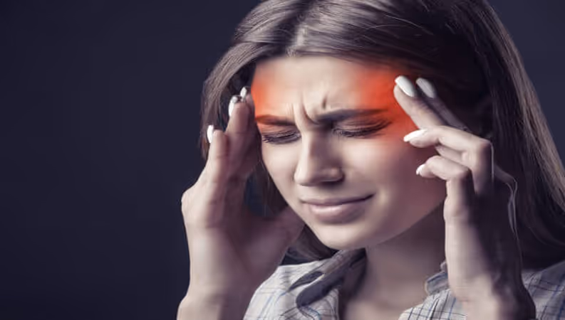 A woman has her hands on her temples, her face contorted in pain.