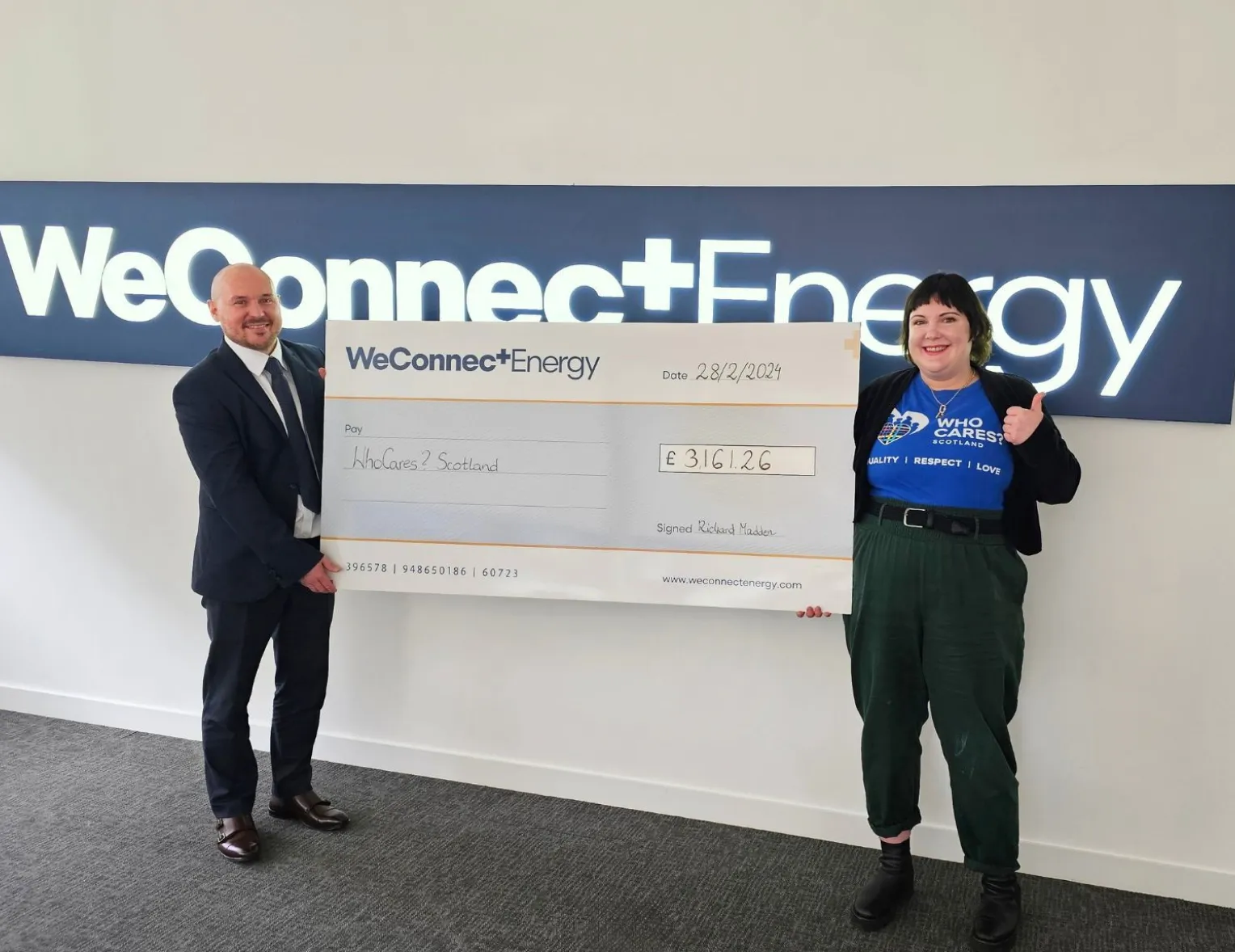 A man and a woman standing next to a large check.