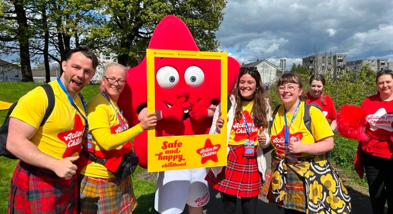 A group of people in kilts holding up a sign.