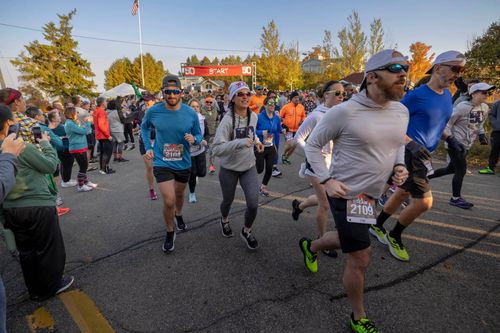 a group of runners taking off at the start line of the Fall50 race