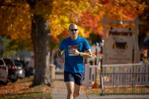 a male runner running in the Fall50 race with yellow and orange leaves in the background