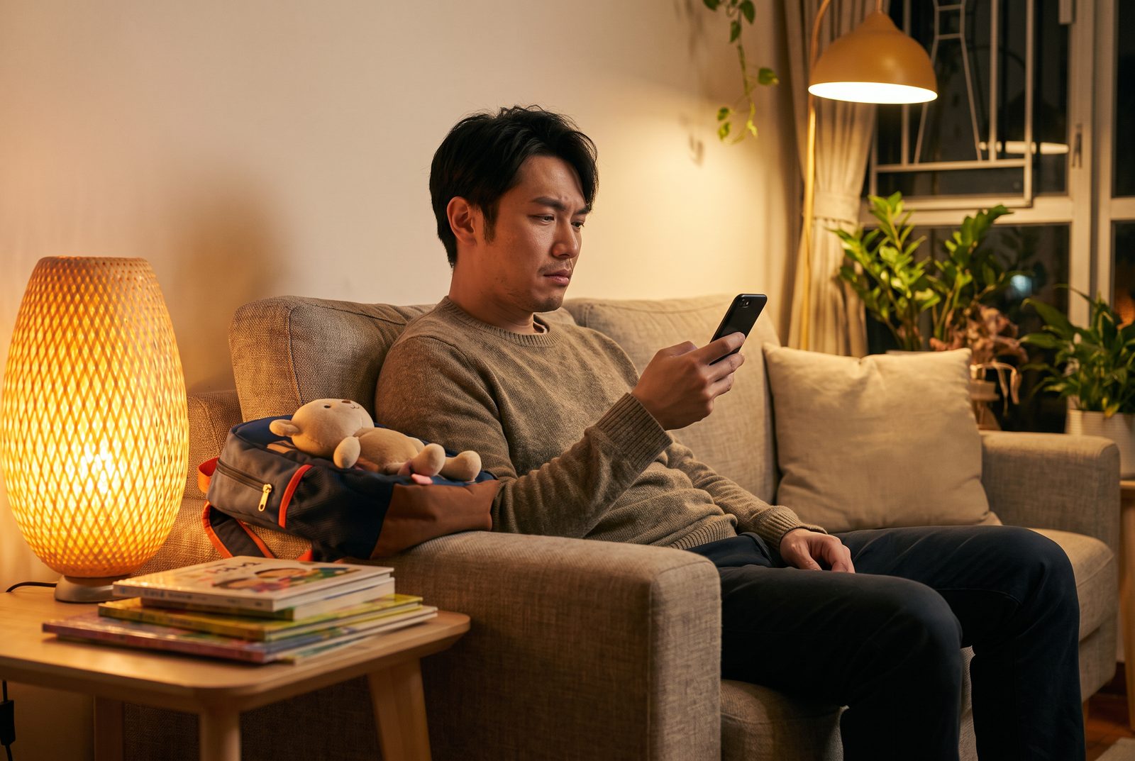 Father scrolling on his phone at night while thinking about parenting pressure