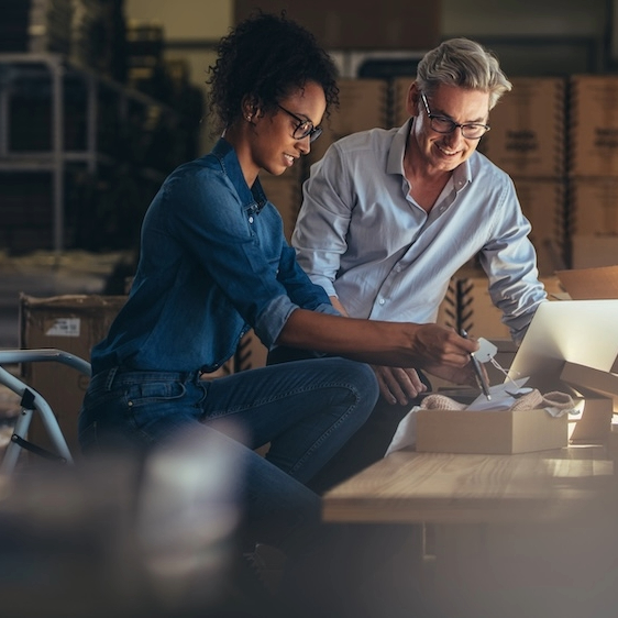 Looking upward between tall modern skyscrapers against a partly cloudy blue sky.
