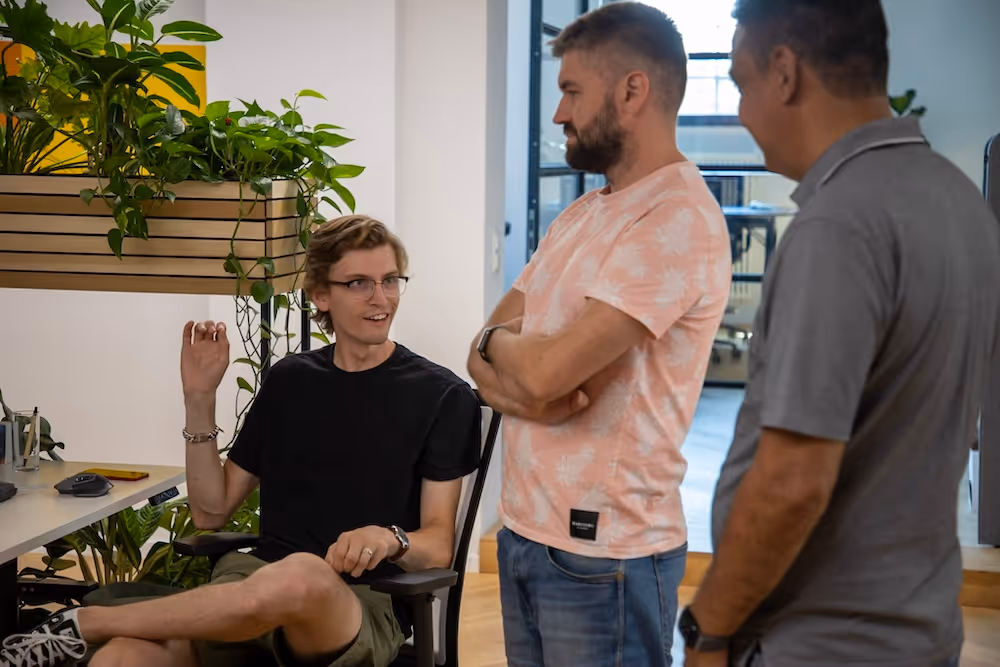 3 foobaristas standing together at a desk and talking