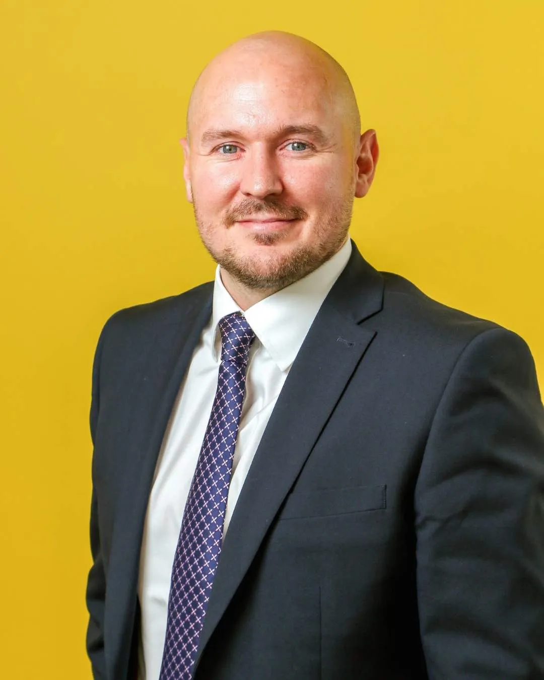 man in suit in front of yellow background