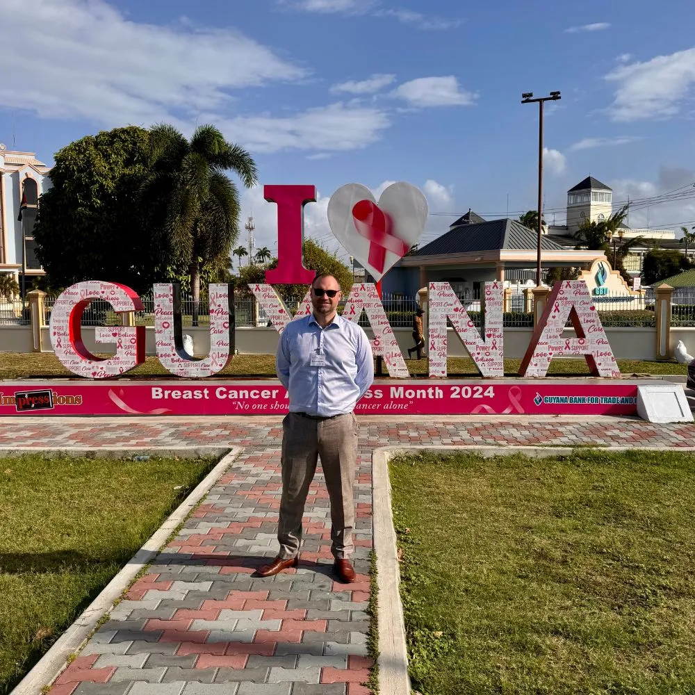 man in front of i love guyana sign