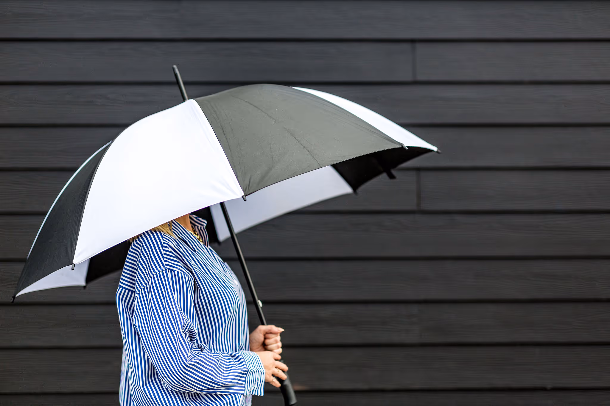 Victoria holding a black and white umbrella over her head.