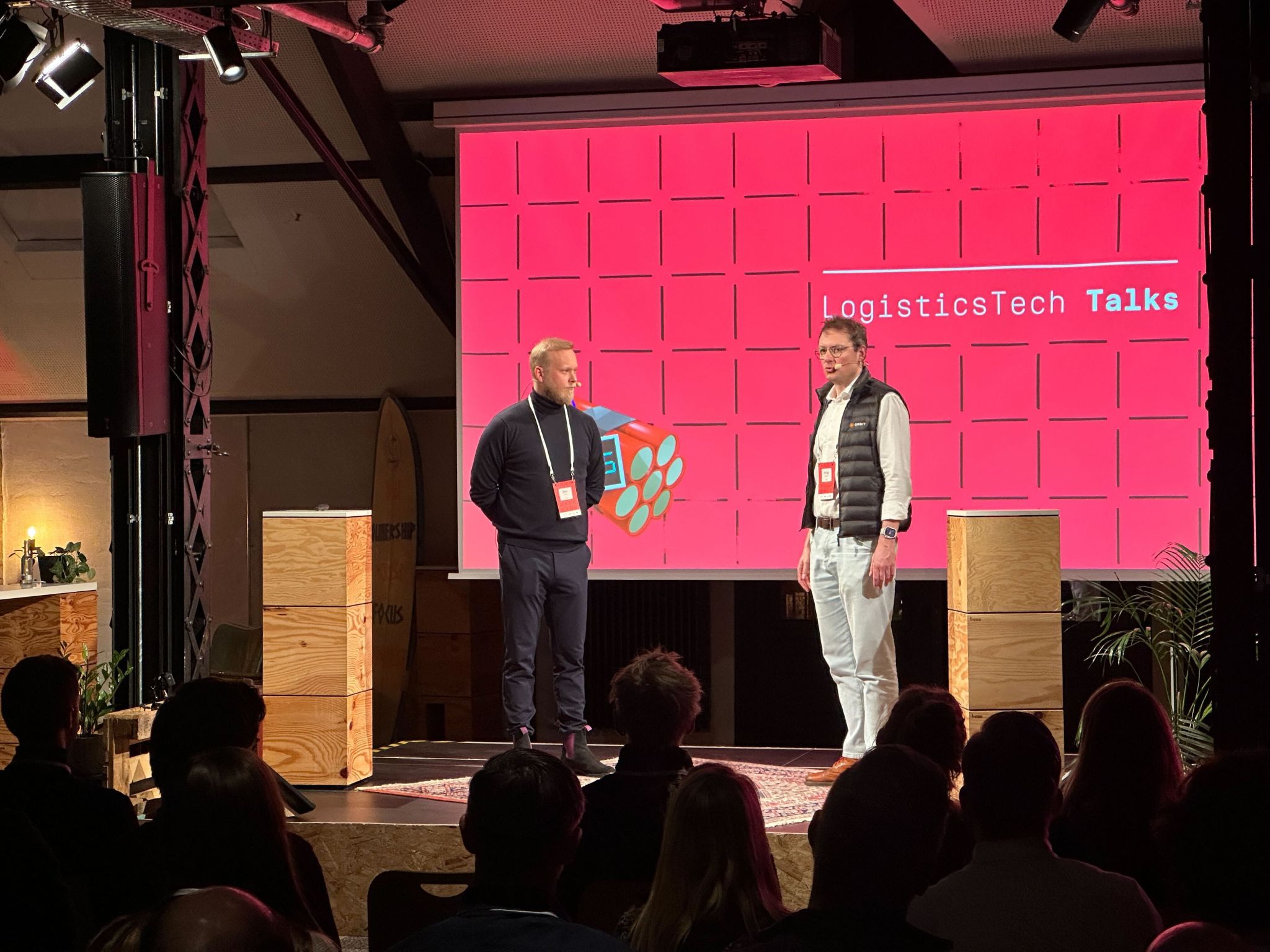 Close-up of the speakers at LogisticsTech Talks, both wearing name tags and presenting in front of a live audience.