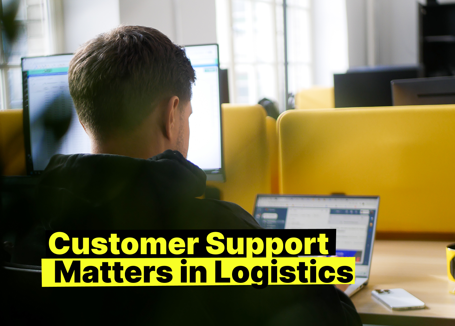 Person working at a modern office desk on logistics customer support, with multiple monitors displaying data, a laptop, and the phrase “Customer Support Matters in Logistics” highlighted in yellow.