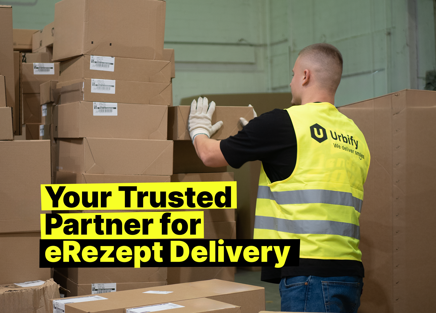 Warehouse worker in a yellow Urbify safety vest handling boxes, with the text “Your Trusted Partner for eRezept Delivery” on a bright yellow background.