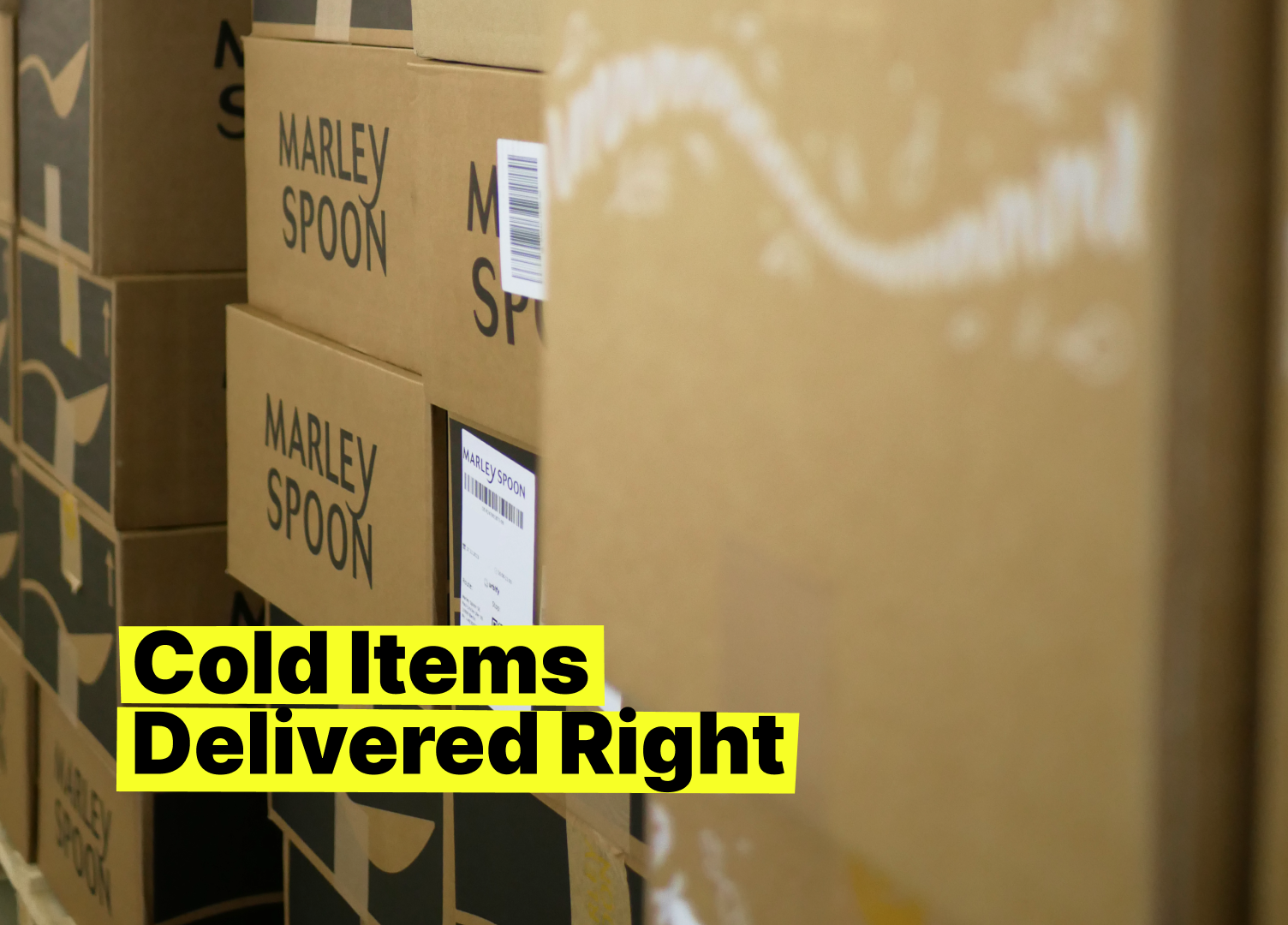 A stack of Marley Spoon cardboard boxes arranged for delivery, with bold yellow text in the foreground reading “Cold Items Delivered Right,” highlighting the focus on reliable cold chain logistics for meal kits and perishable foods