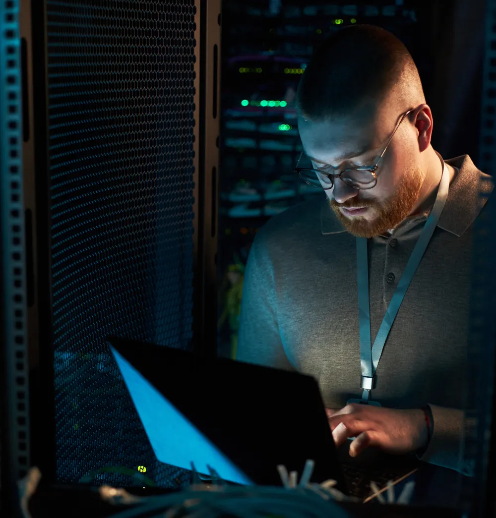 Man looking at a laptop in a server room