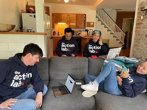 Four people wearing Action Lab shirts doing work on a couch