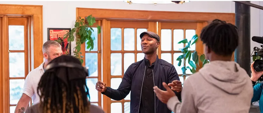 The musician Aloe Blacc in a circle singing with another musician and two students