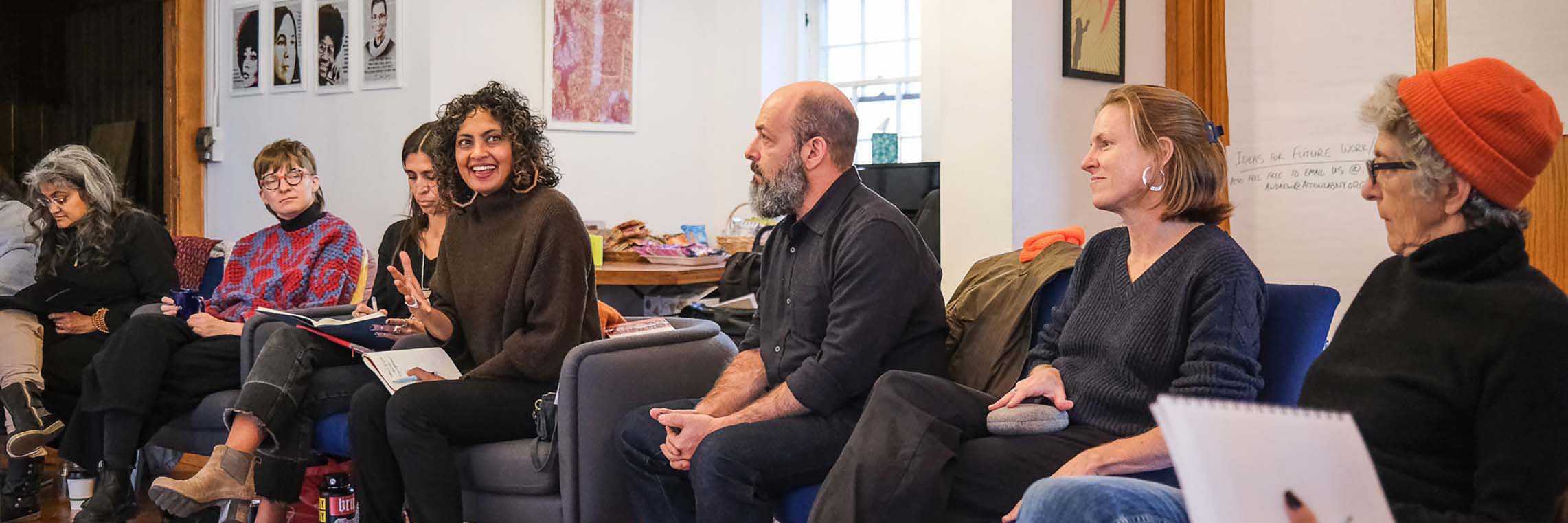 People seated in a circle listening to one woman talk