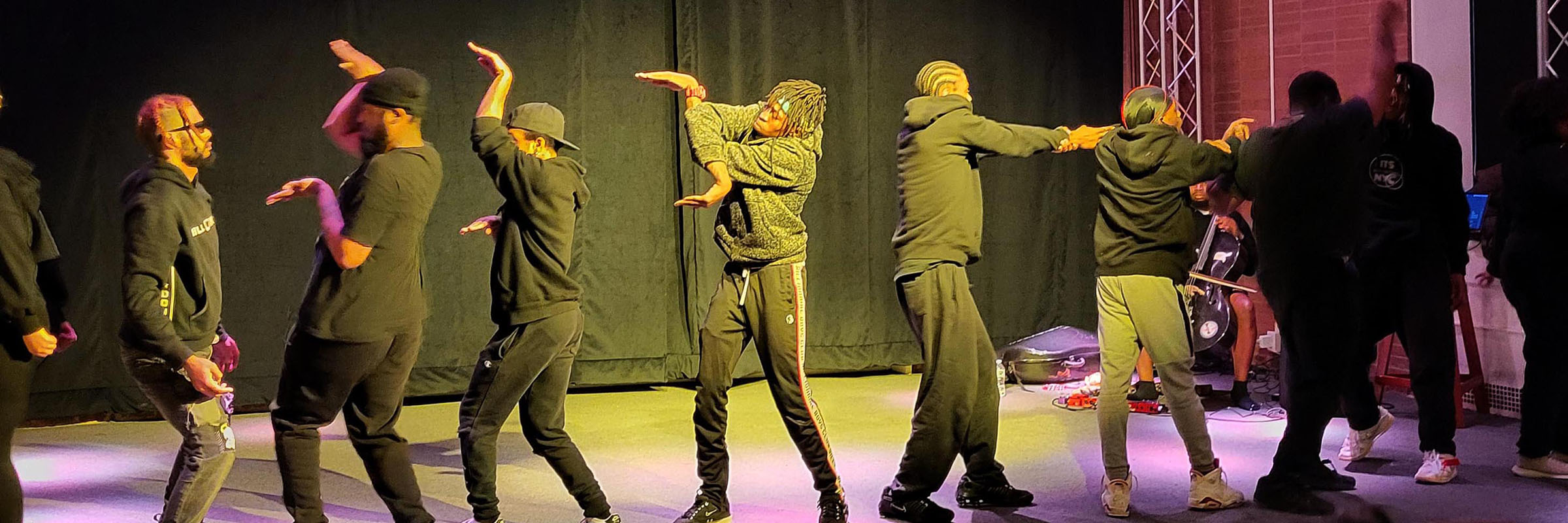 Young men wearing sweats and t-shirts performing a dance on a stage