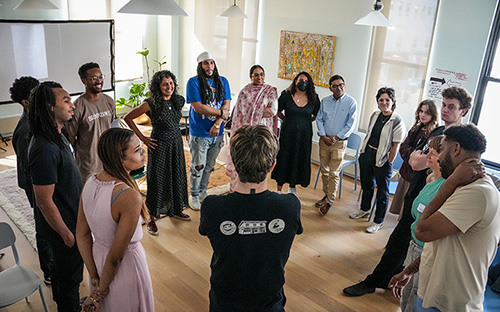 Group of people standing in a circle during a workshop or discussion in a bright room.