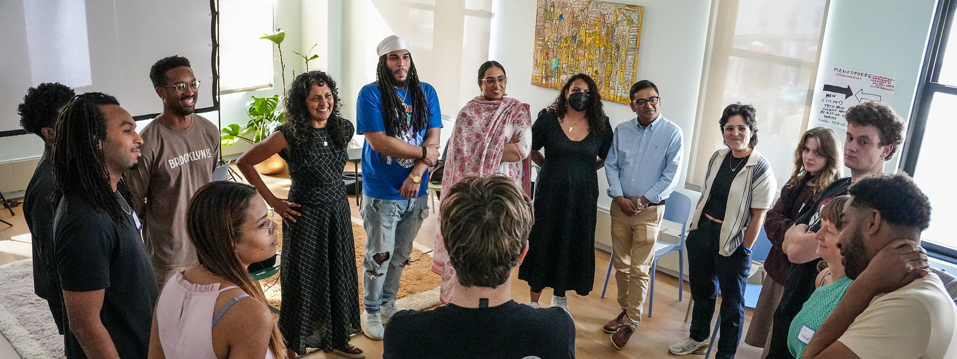 Group of people standing in a circle during a workshop or discussion in a bright room.