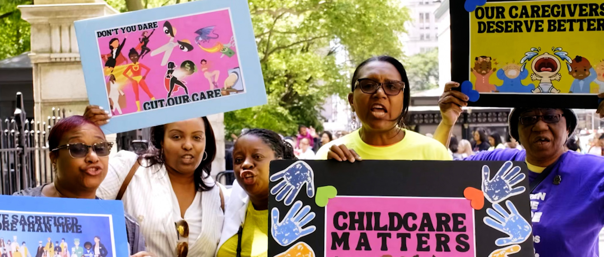Childcare workers holding protest signs calling for better caregiver support.