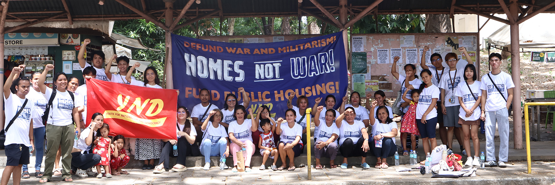 Young activists posing with a ‘Homes Not War’ banner supporting public housing.